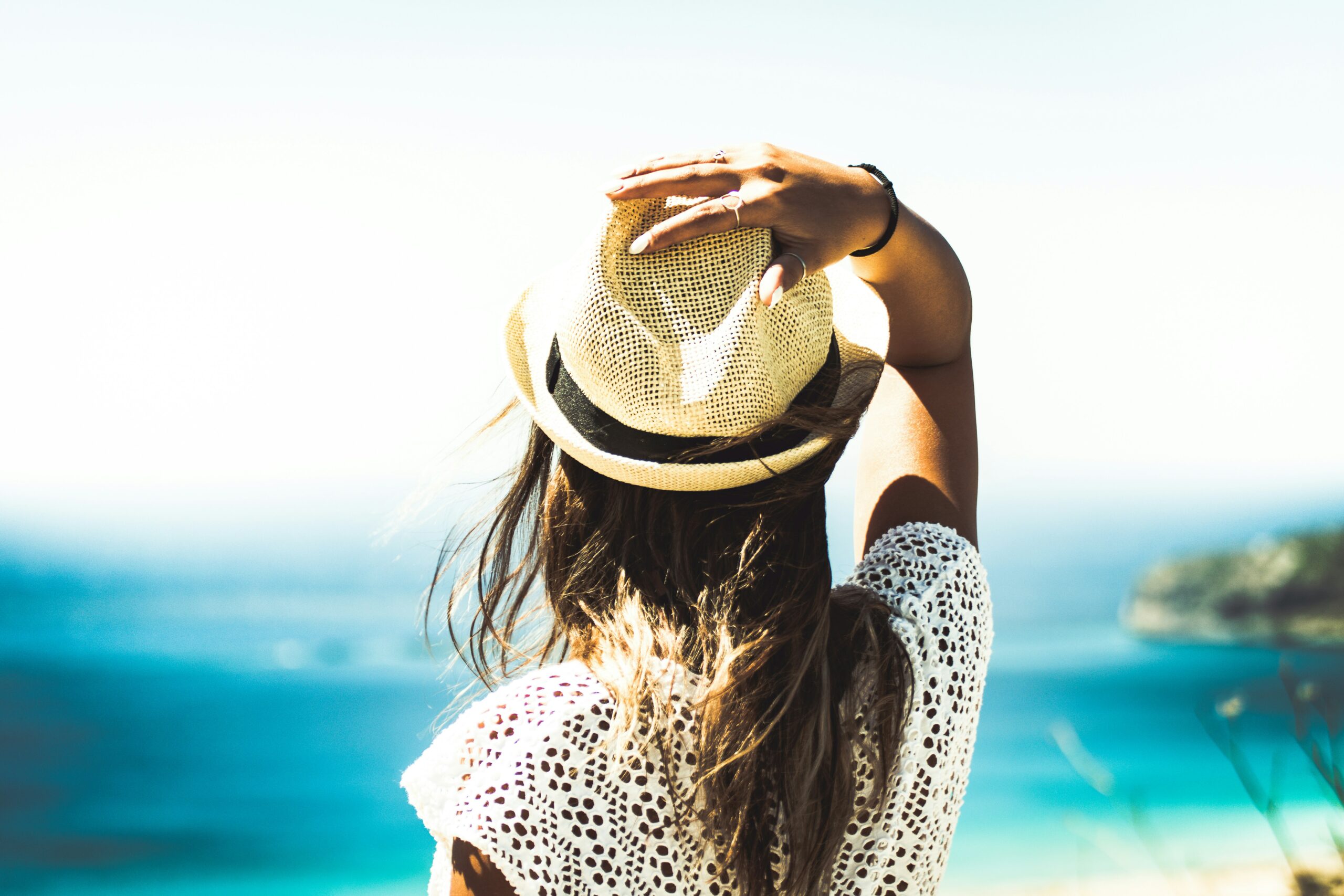 young woman wearing a fedora and looking at the ocean | hiddenriverhealing.com